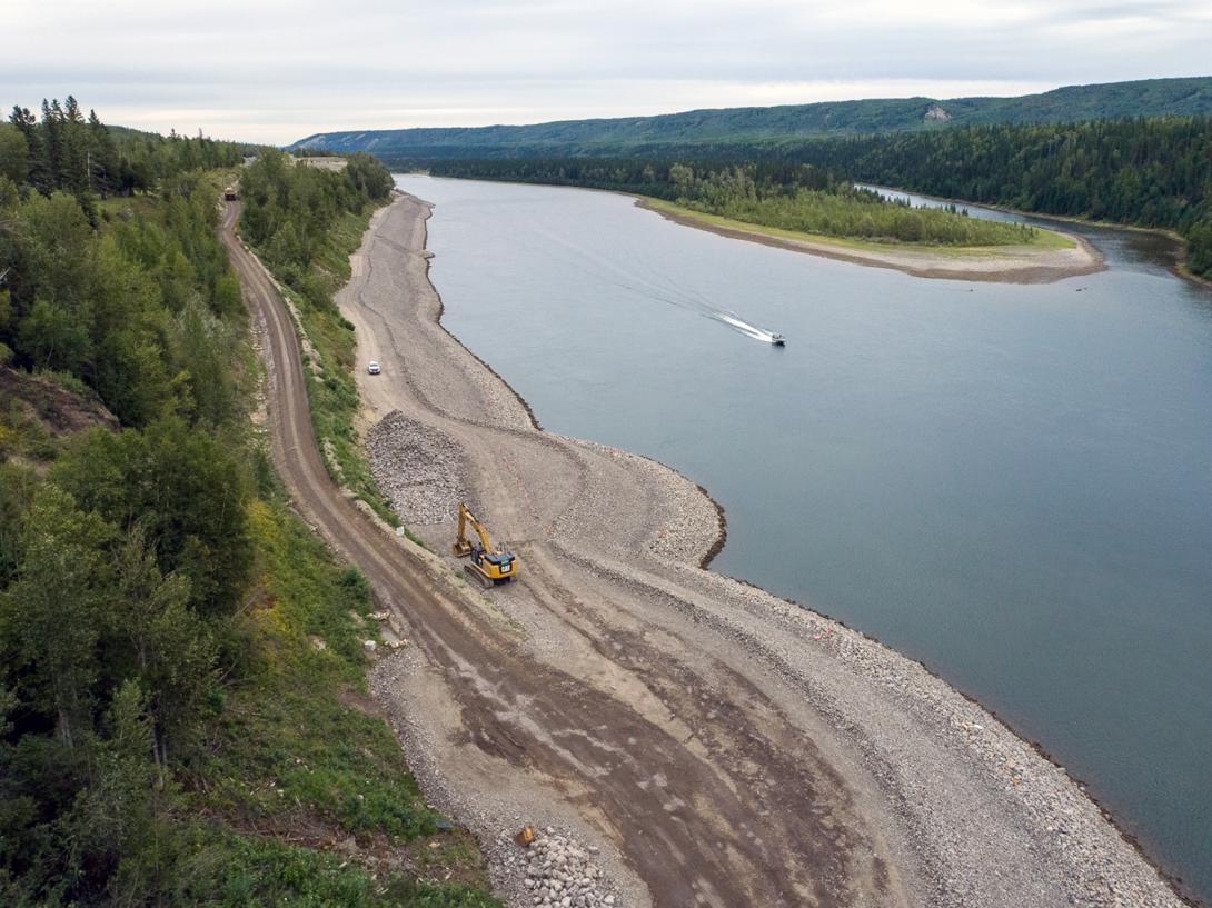 An excavator at the bottom of the DA Thomas Road hill piles riprap on the Hudson’s Hope shoreline protection berm. | August 2021