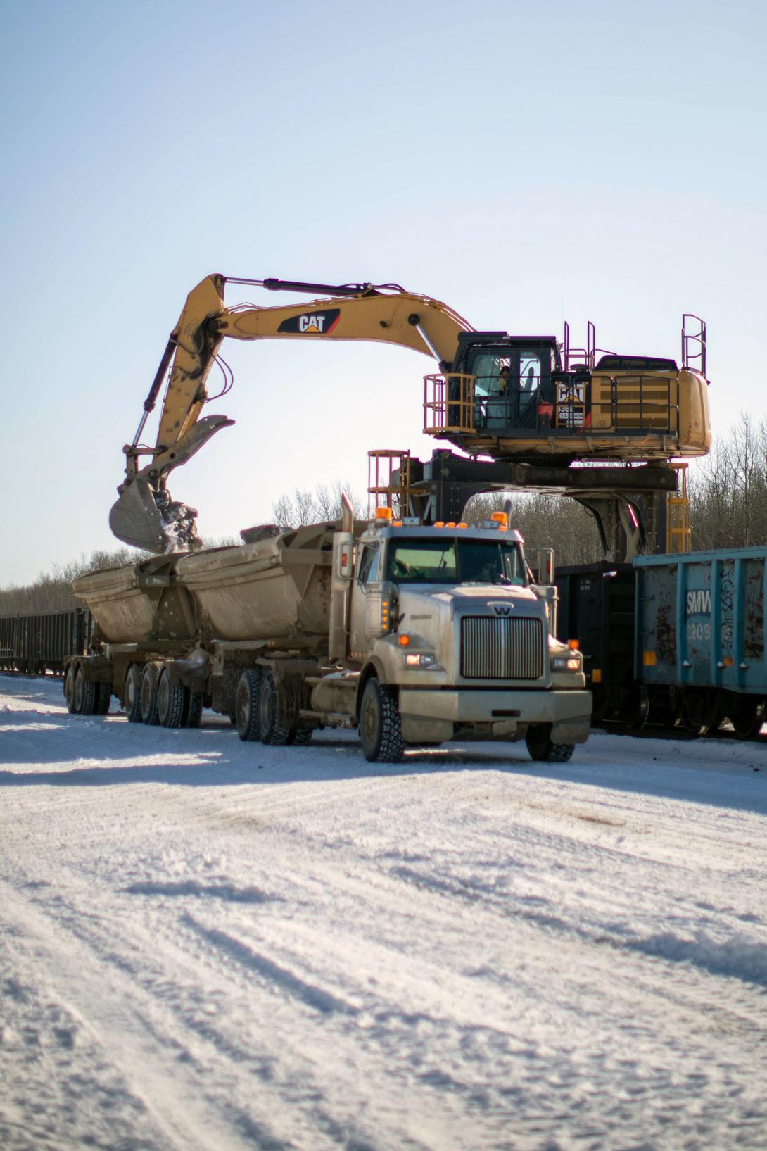 A side-dump truck is loaded with rip-rap to haul and stockpile on site for river diversion. | April 2020