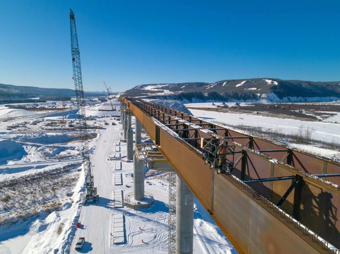 Crews at the Halfway River bridge use a survey buggy to measure the angle of the bridge girders before installing the bridge deck. All twelve bridge piers are complete and steel girders are being installed on top. | February 2021