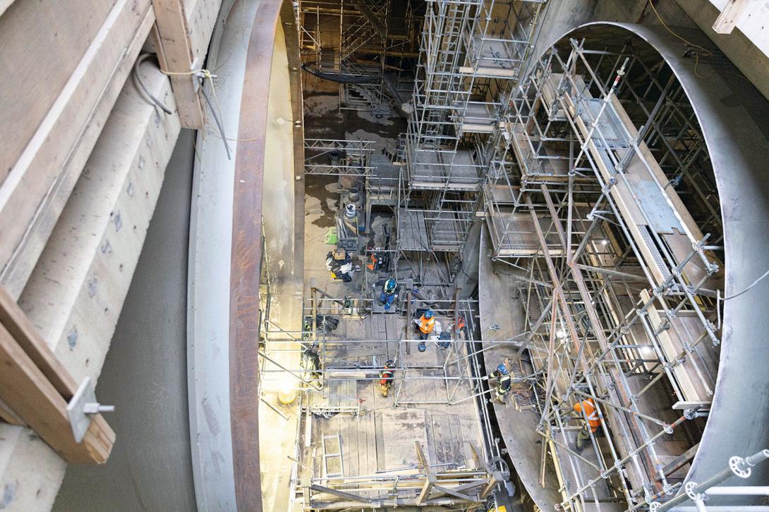 Water flows into the turbine units through penstocks. On the right is the downstream end of a penstock where scaffolding is being removed. On the left is the entrance to a turbine unit. | December 2023