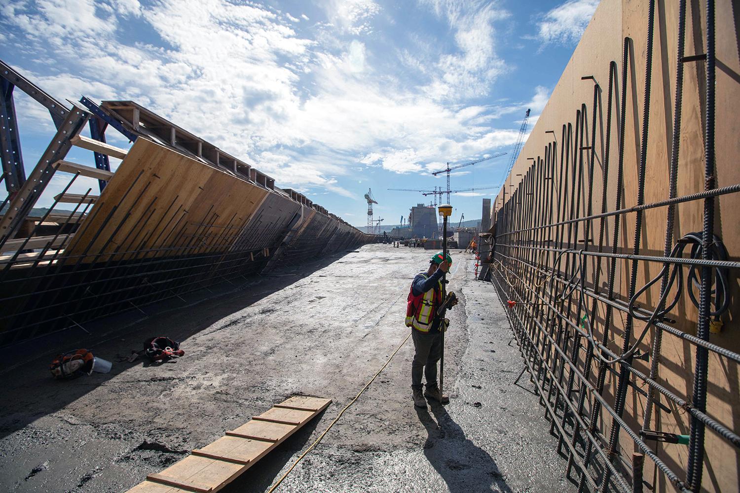 Workers install roller-compacted concrete formwork between reinforced steel on the dam buttress. The distance between the blue cantilever supports is approximately 90 centimetres. | June 2021