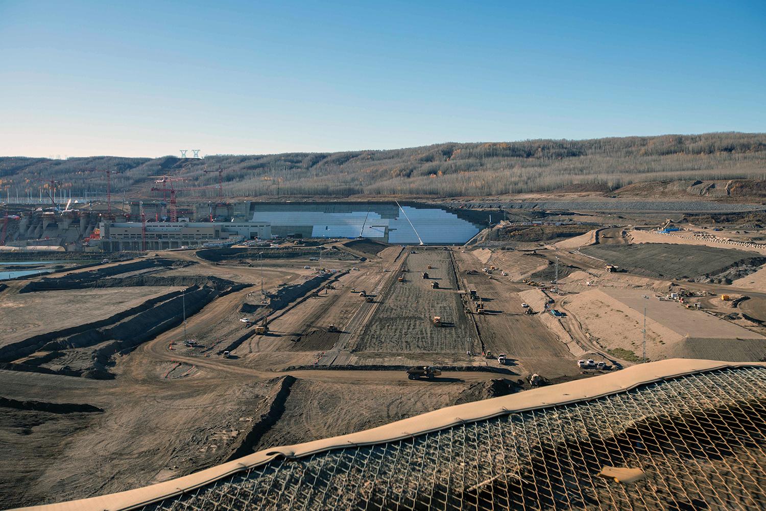 Glacial till material is placed in the dam core trench; the partially insulated dam and core buttress is seen in the background. | October 2021