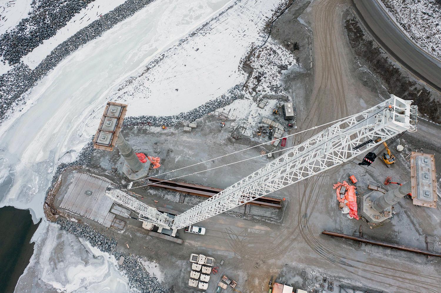 A crane at the Cache Creek bridge realignment construction site prepares to install girders. | December 2021