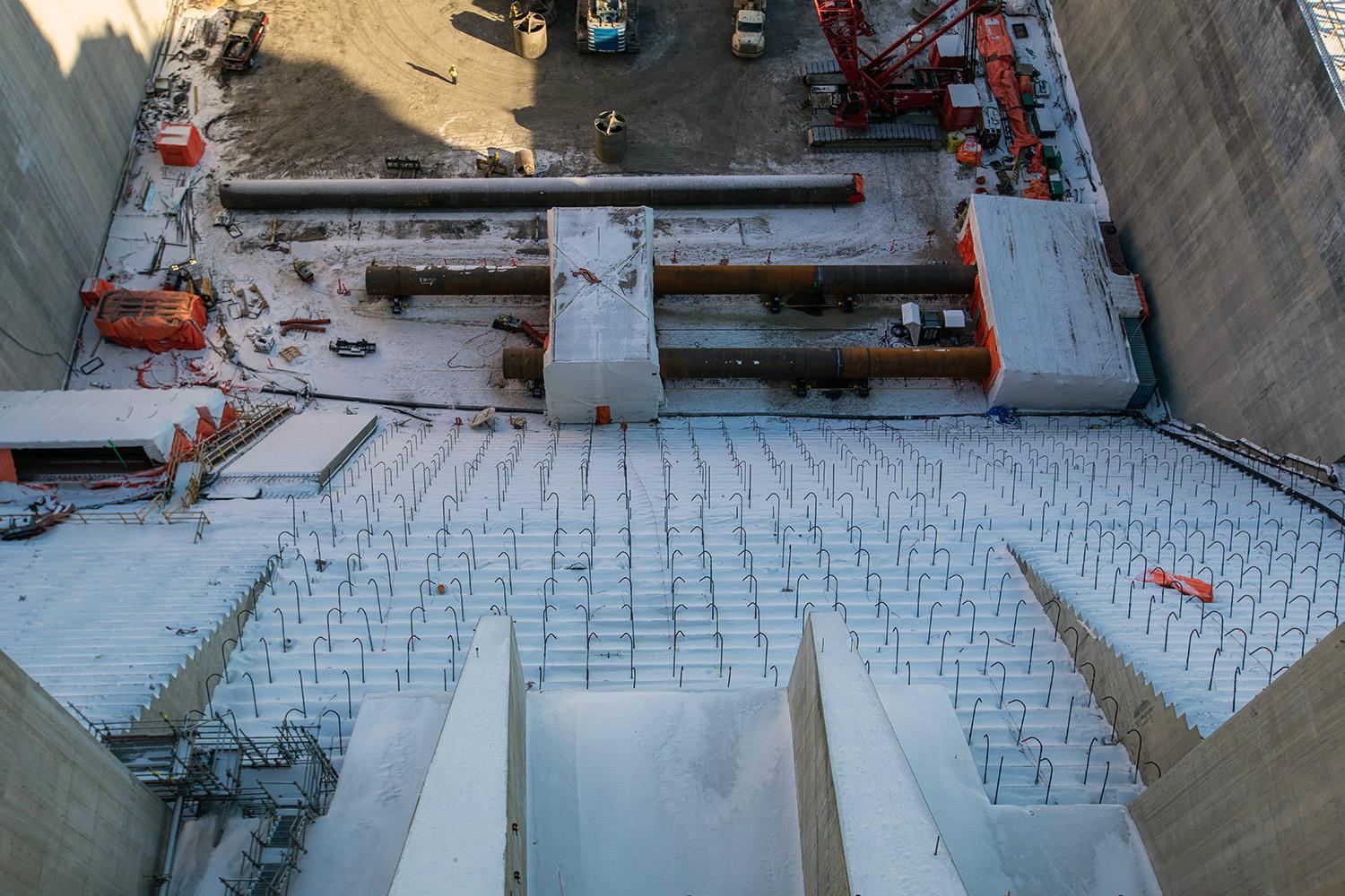 Foundation pile sections are welded at the base of the spillway stilling basin, and rebar dowels are placed to secure concrete. | February 2022