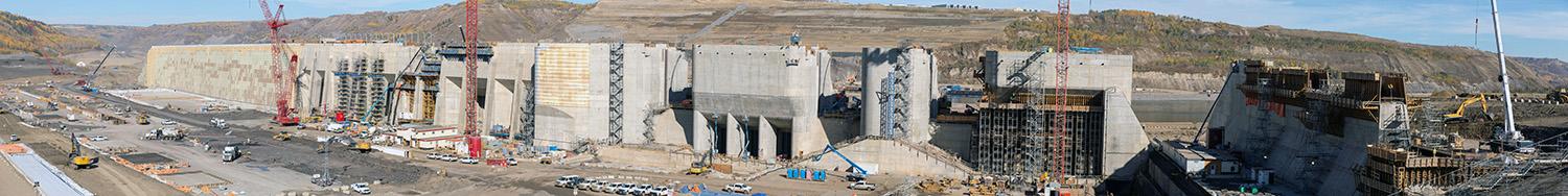 From right-to-left: the passive spillway, spillway upper headworks, six intake gates, and roller compacted concrete buttress. In front: Approach channel. | September 2022