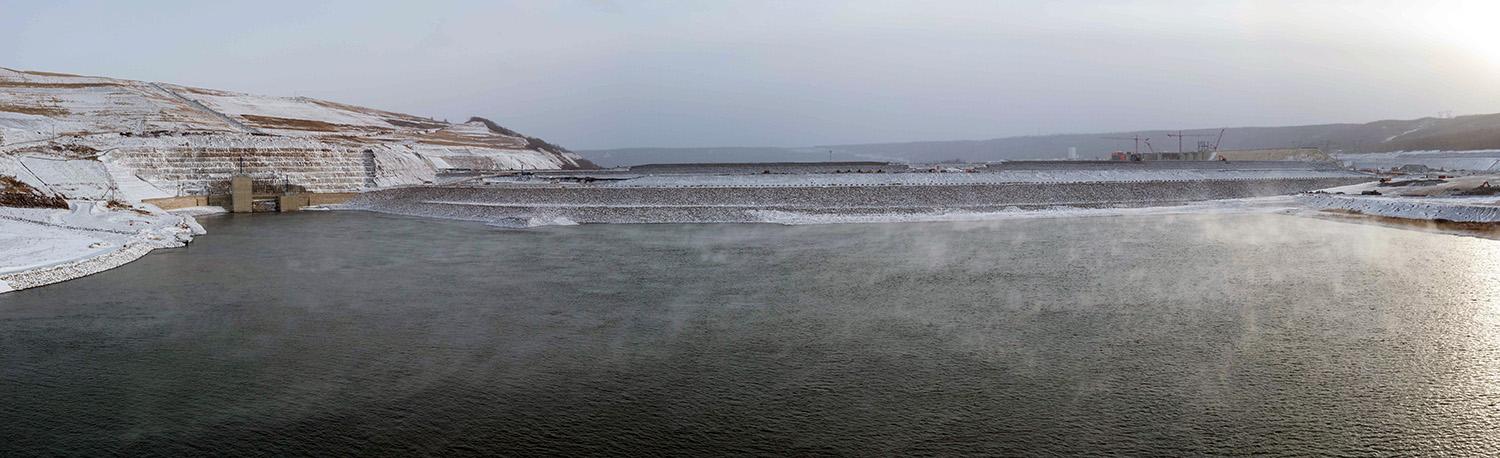 The inlet portals (left) where the Peace River enters the diversion tunnels, and the earthfill dam (centre) being built. | November 2022