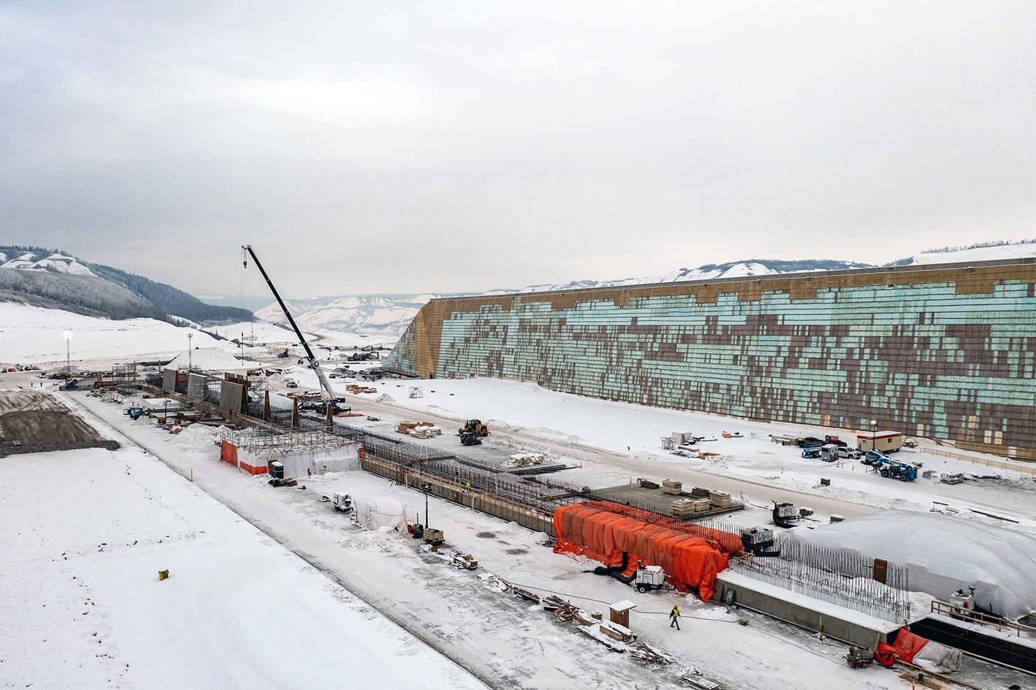 Under the heated tarps, concrete is curing for the centre wall of approach channel. Further back, crews install formwork and reinforce steel. | January 2023