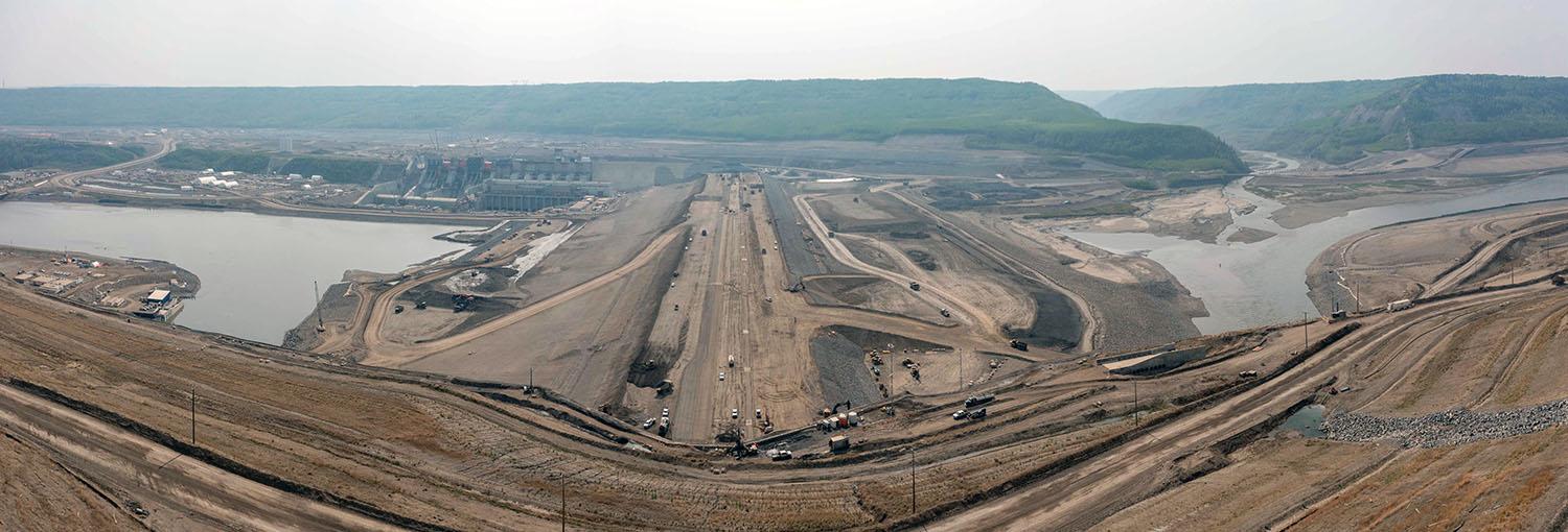 South-facing view over the dam where layers of glacial till are compacted to reach the final elevation of 60 metres above the riverbank. | May 2023