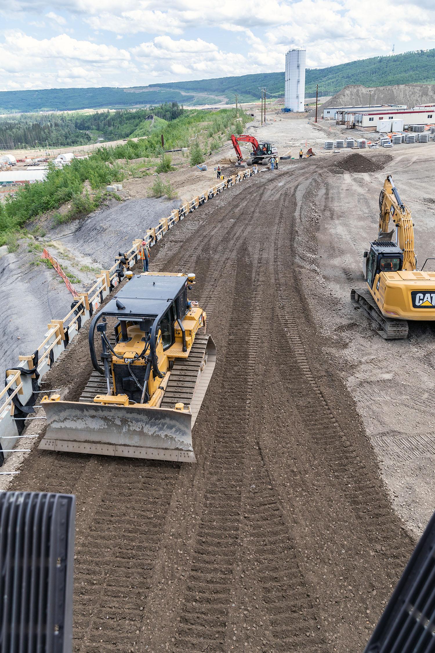 Aggregate is placed and compacted against the precast panels of the mechanical stabilized earth wall on the east side of the auxiliary spillway. | May 2023