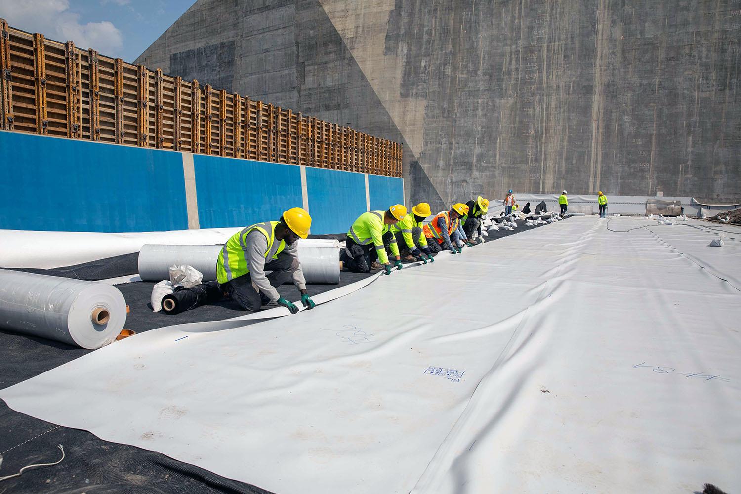 Crews place the waterproof liner in the approach channel. | June 2023