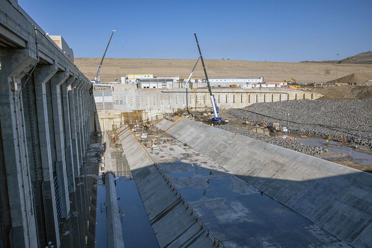 As water leaves the powerhouse on the left, it enters the tailrace where it is slowed before being directed downstream to continue the river flow.