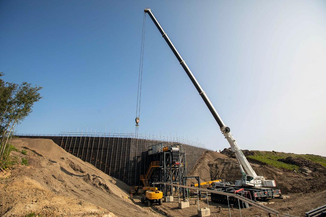 This mechanically stabilized earth wall is part of the updated conveyor loading system. Mine trucks drive on top to dump glacial till into the hopper. | August 2021