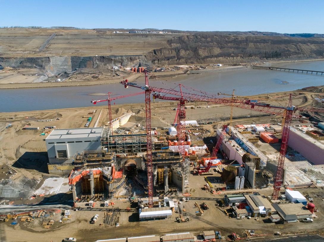 The intake gates for units 1, 2 and 3 – viewed left to right facing the north bank. The main service bay, structural steel assembly, and powerhouse and generating station are in the centre of the photo. | April 2020