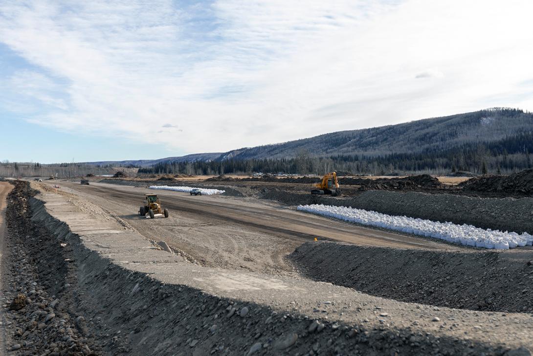 Developing an aggregate source near Lynx Creek for the Highway 29 road realignment. The white bags are filled with aggregate and stored for use as shoreline protection. | March 2020