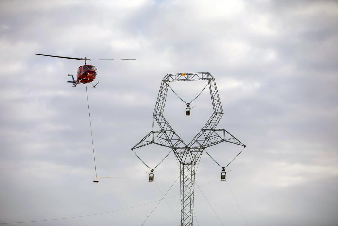 As part of transmission line installation, a helicopter pulls the sock line through the traveller, like a pulley. | March 2020