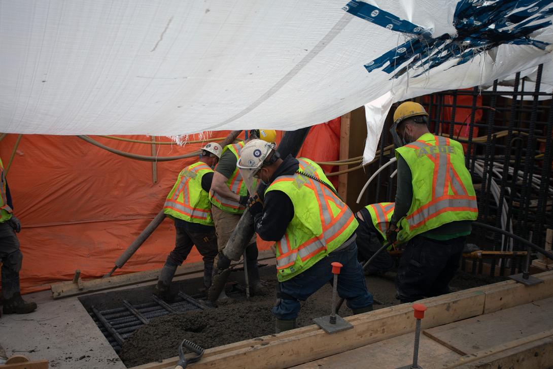 Workers place concrete at the spillway headworks. | April 2021