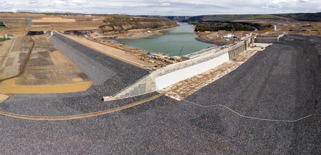 The Peace River enters the diversion inlet portal at top left and flows around the dam to exit through the diversion outlet portal. The approach channel on the right will direct water from the future reservoir to the intakes. | May 2024