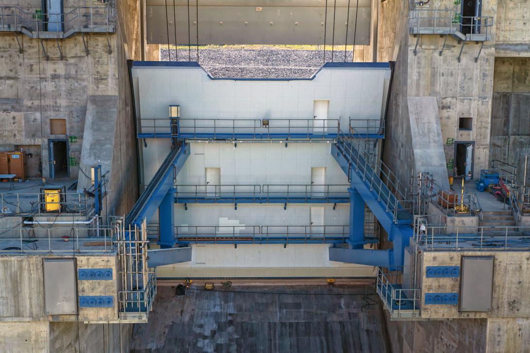 Concrete finishing work is underway on the door sill of the second spillway operating gate. The spillway gates are lifted by hoist cables and pivot on axis points. | July 2024