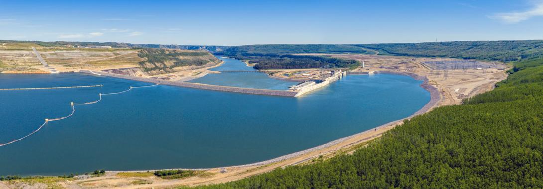 Downstream view towards the Site C dam and generating station. Permanent booms continue to direct debris to the north bank away from the approach channel to be removed from the reservoir. | July 2025