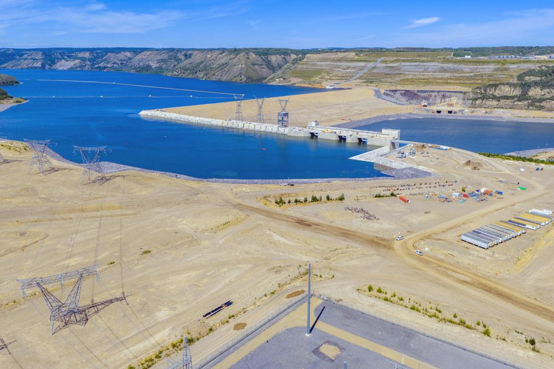 View toward the approach channel, intakes, and spillways. Transmission lines between powerhouse and substation at lower left. | July 2025