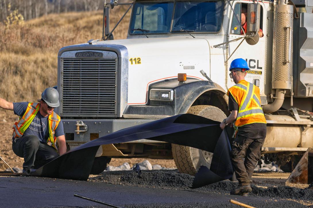 Rubber matting is laid between the first and second lifts of pavement to get a clean join, and then it is removed. | October 2025